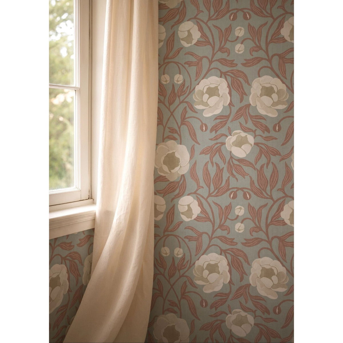 Detail van Summer Gray Peony Blue & Brown bloemenbehang naast een raam met een licht gordijn