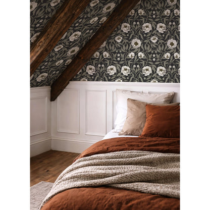 Peony Charcoal bloemenbehang van Summer Gray onder een schuin dak met houten balken en een bed met roestbruin beddengoed