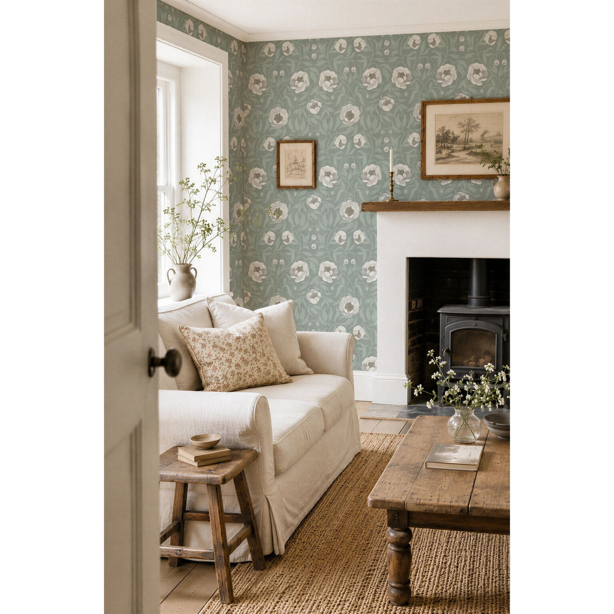Interieur met Peony Green bloemenbehang van Summer Gray in landelijke romantische stijl, met een lichte bank en houtkachel.